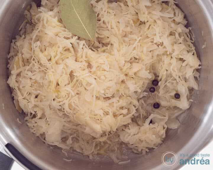 A pan with sauerkraut, wine, juniper berries and bay leaves