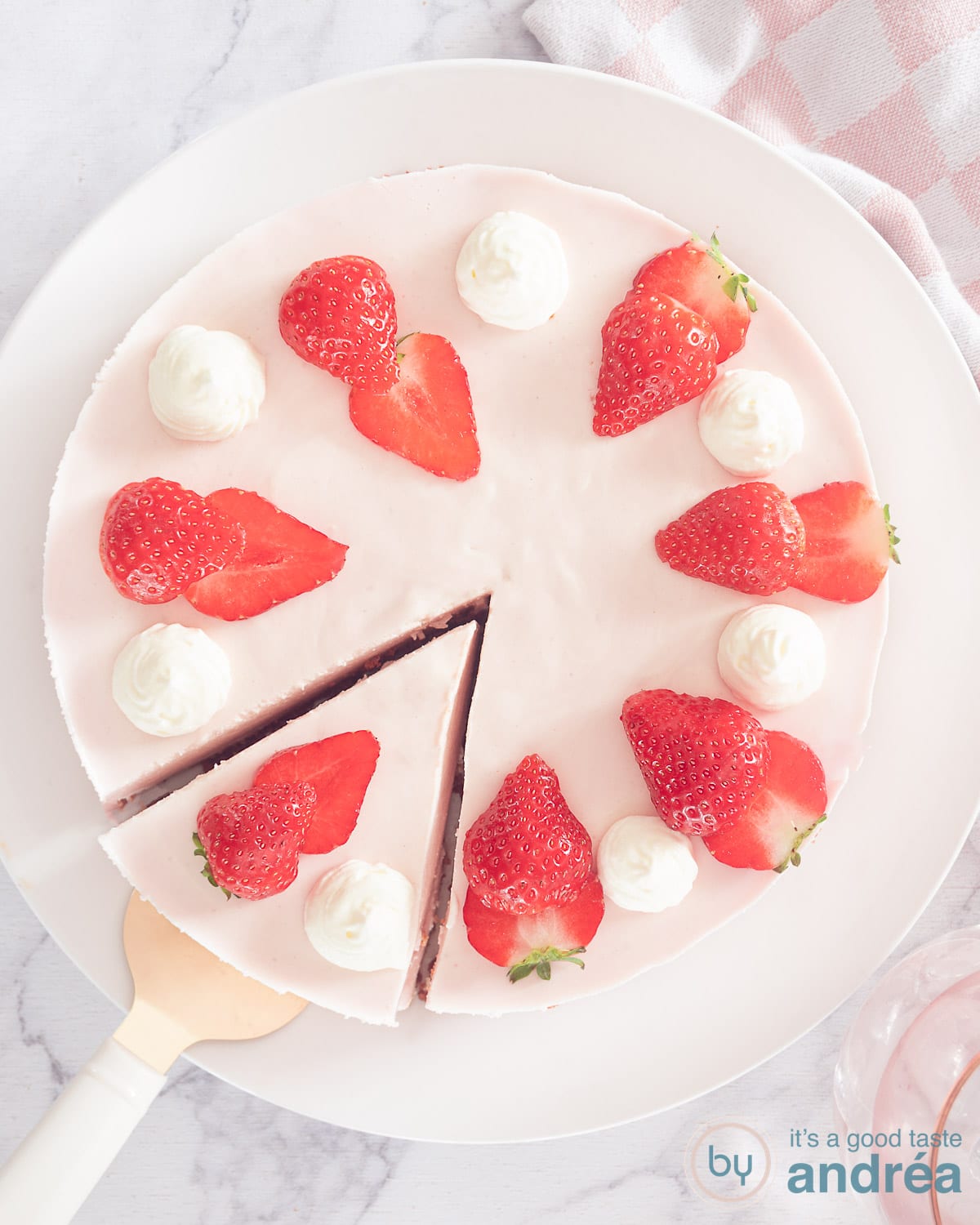 A photo from above of a strawberry cheesecake with a point cut out of it. A white background.