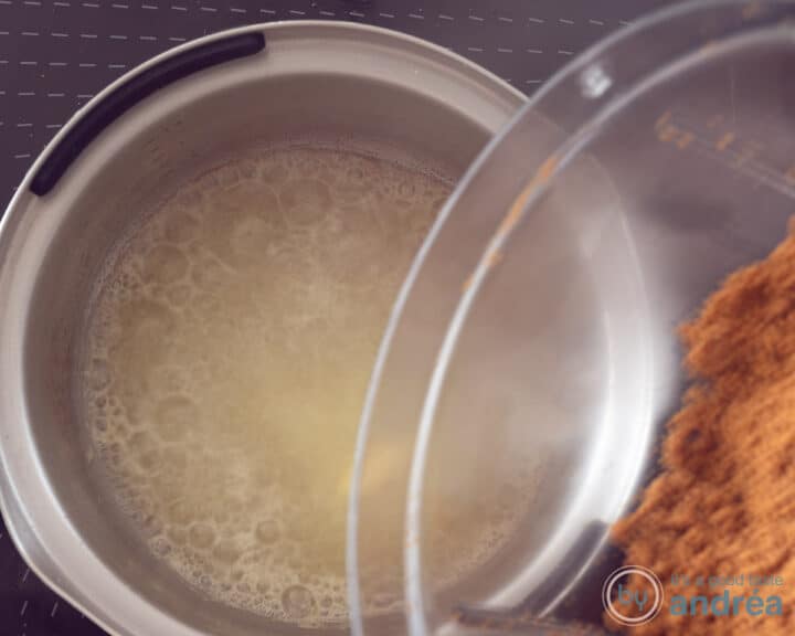 A saucepan with melted butter to which speculoos cookie crumbs are added.