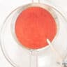 Strawberry pulp is sieved over a glass bowl