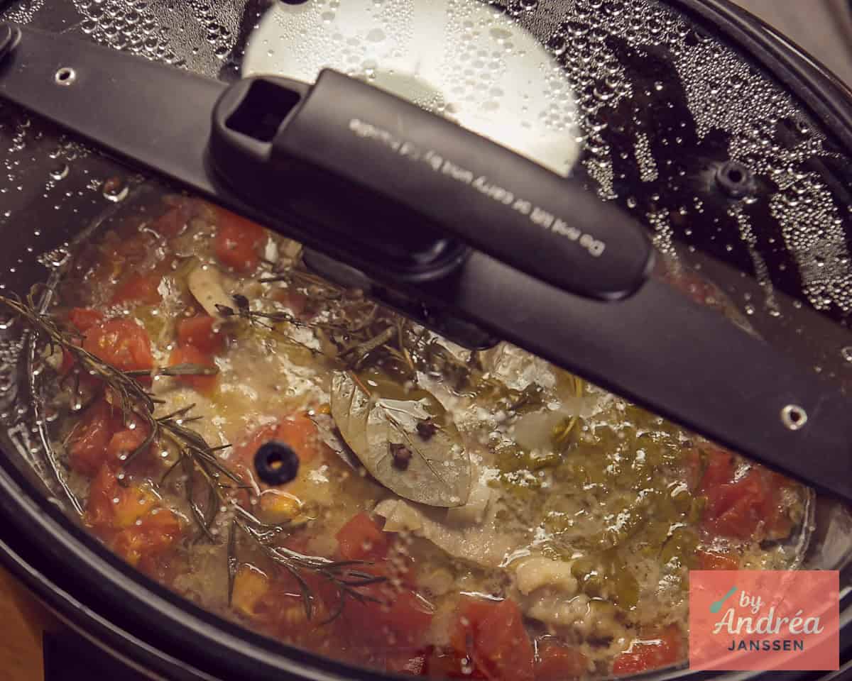 A lid on a slow cooker with ham steaks and sauce