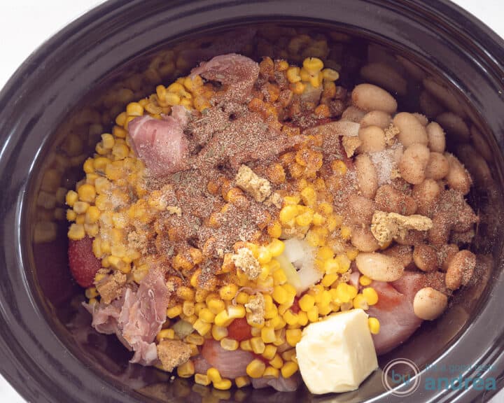 Onion, corn and butter are added to the meat in the slow cooker.