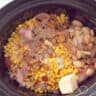 Onion, corn and butter are added to the meat in the slow cooker.