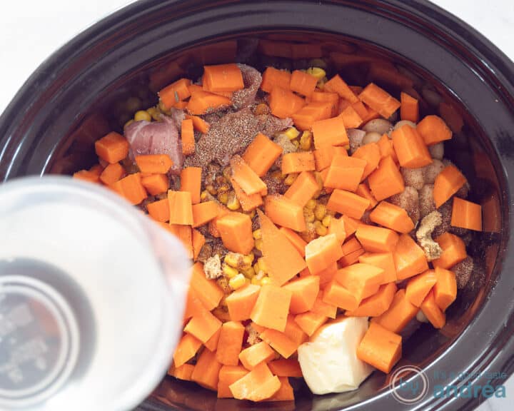 Water is added to the ingredients in the slow cooker.