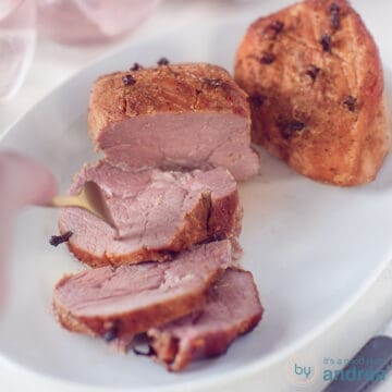 A square photo with two hams covered with a cola mustard sauce. Three slices cut off. A fork pierces a slice