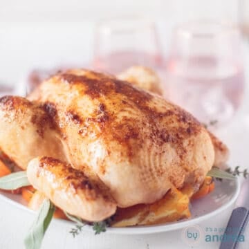 A square photo showing a roasted chicken with orange and honey glaze on a white plate