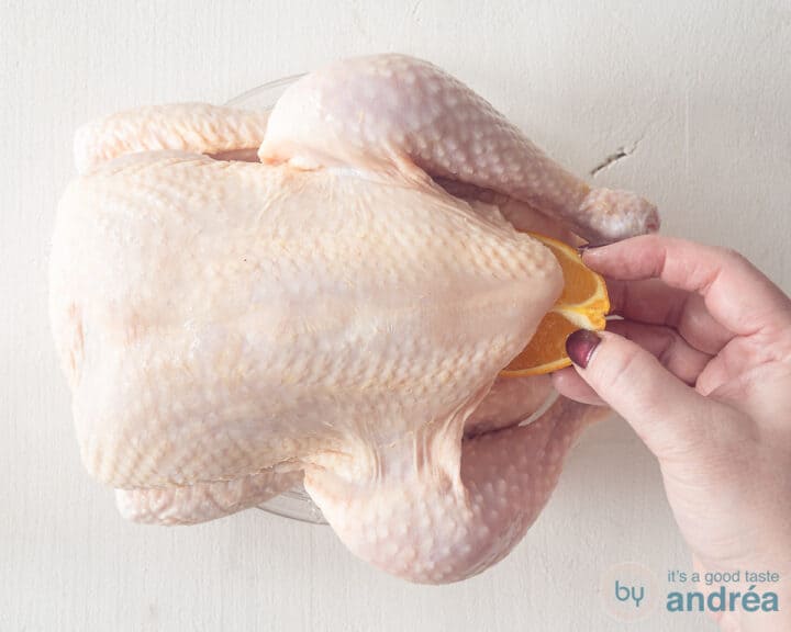 Push fresh herbs and orange into the cavity of the whole chicken.