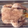 A whole chicken on a rack in an oven dish. Rubbed with spice rub