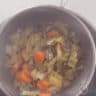 A sieved pot of chicken soup, with a sieve of leftover vegetables on top.