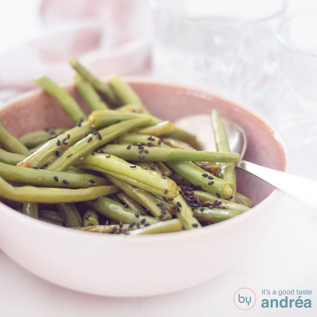 A square picture with a pink bowl with Asian style stir-fried green beans