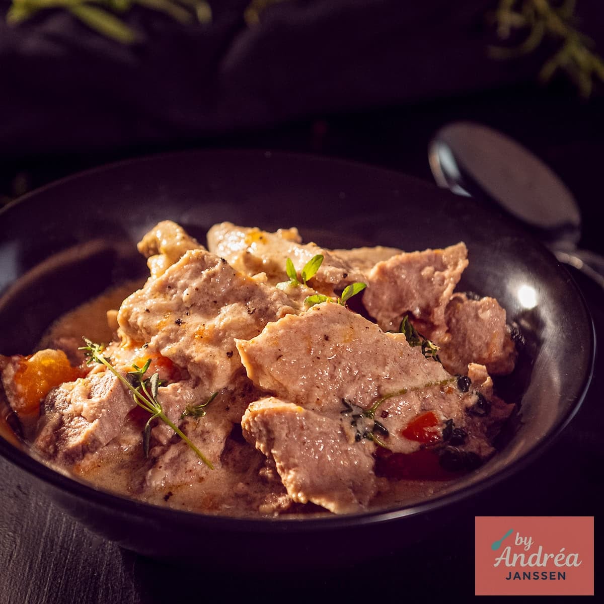 A square photo with a black plate with ham steaks in a delicious cream sauce