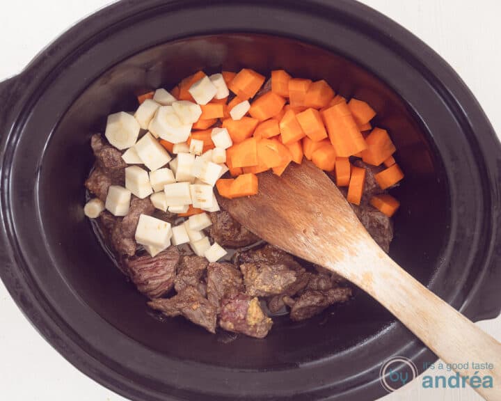 A slow cooker filled with meat, parsnips and carrot cubes