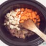 A slow cooker filled with meat, parsnips and carrot cubes