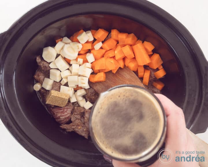 A slow cooker filled with meat, parsnips and carrot cubes. Beer is served