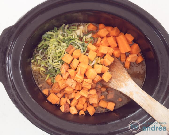 Slow cooker filled with beer broth, winter vegetables and meat.