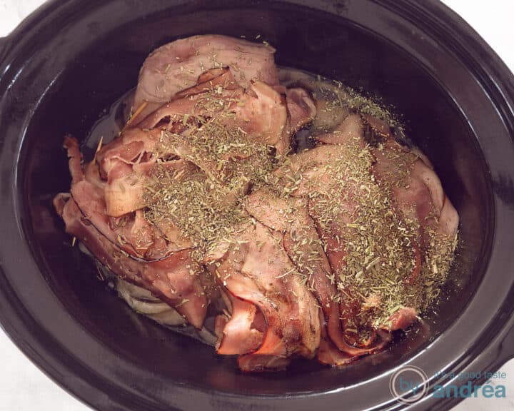 Roast beef in the slow cooker wrapped in bacon and sprinkled with rosemary and thyme.
