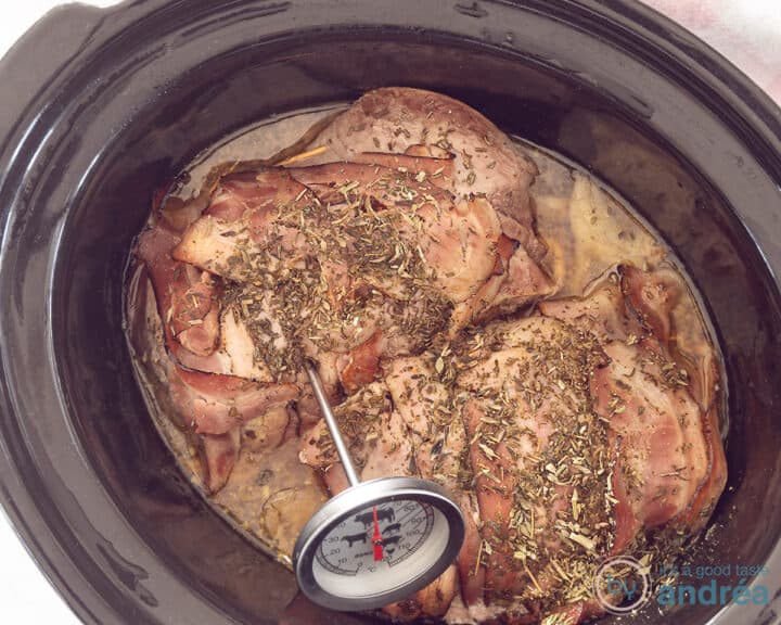 Roast beef in the slow cooker with a meat thermometer inserted.