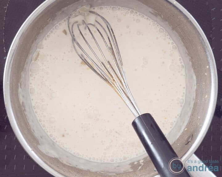 Coconut milk in a saucepan with a whisk in it