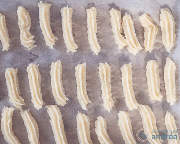 Churros, unbaked, on a baking tray lined with baking paper