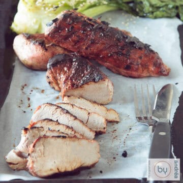 A square photo with two Char Siu, 1 of which is cut into strips on a baking sheet