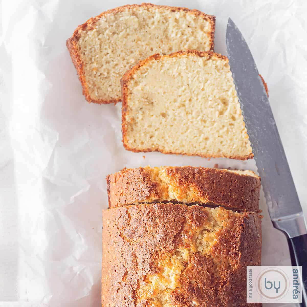 A square photo of an applesauce cake with two slices cut off and lying flat. A knife is next to it.