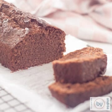 A square photo of a rack with a chocolate cake on it with two slices of cake cut off and lying in front of it.