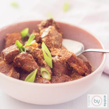 A square photo of a pink bowl with stew: Daging Roedjak from Indonesia made in the slow cooker. A white background.