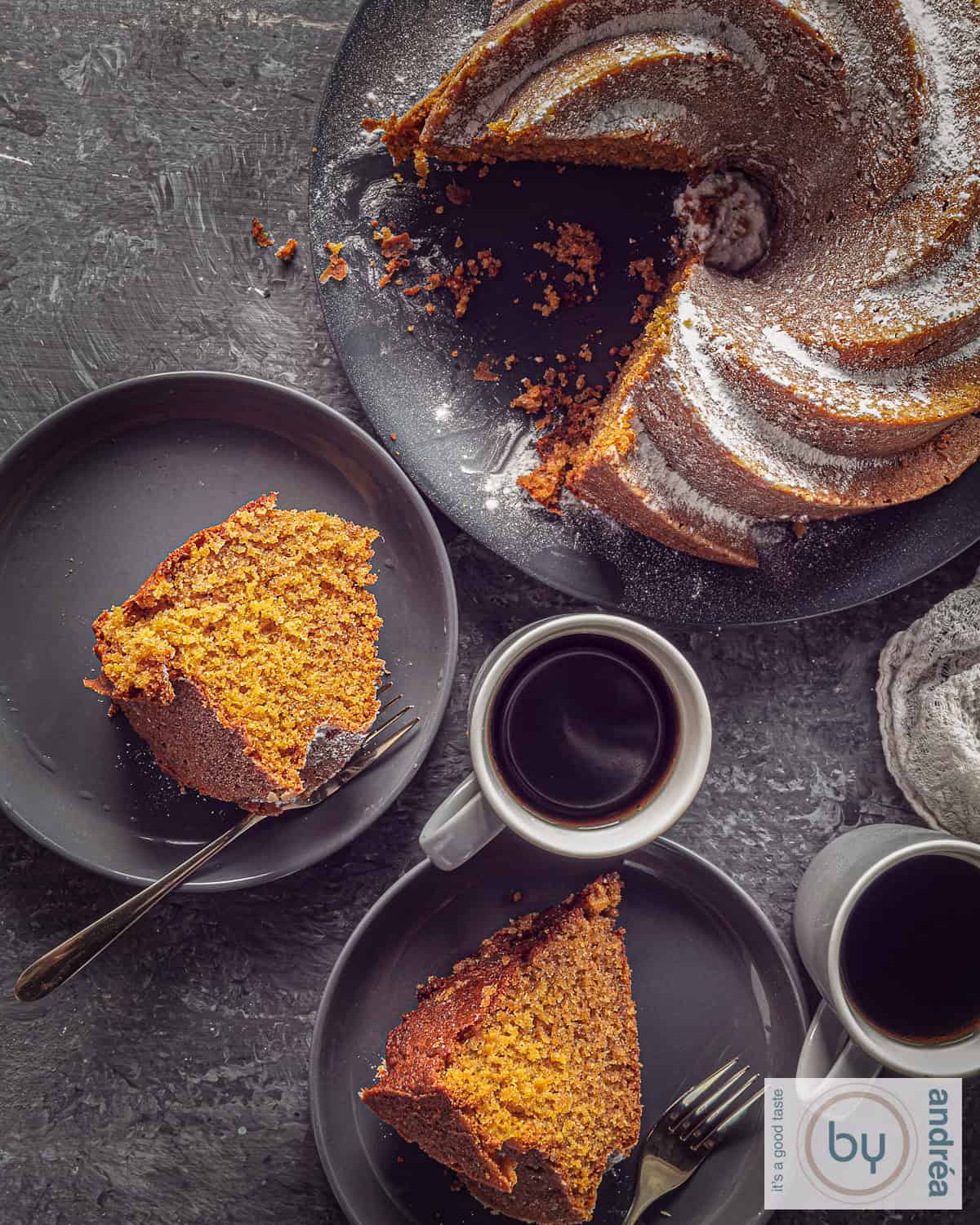 A top-down photo of a pumpkin bundt cake with two pieces cut out of it and lying on a gray plate.