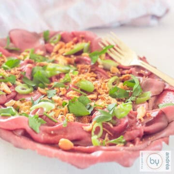 A square photo with a bowl filled with Asian style roast beef carpaccio salad.