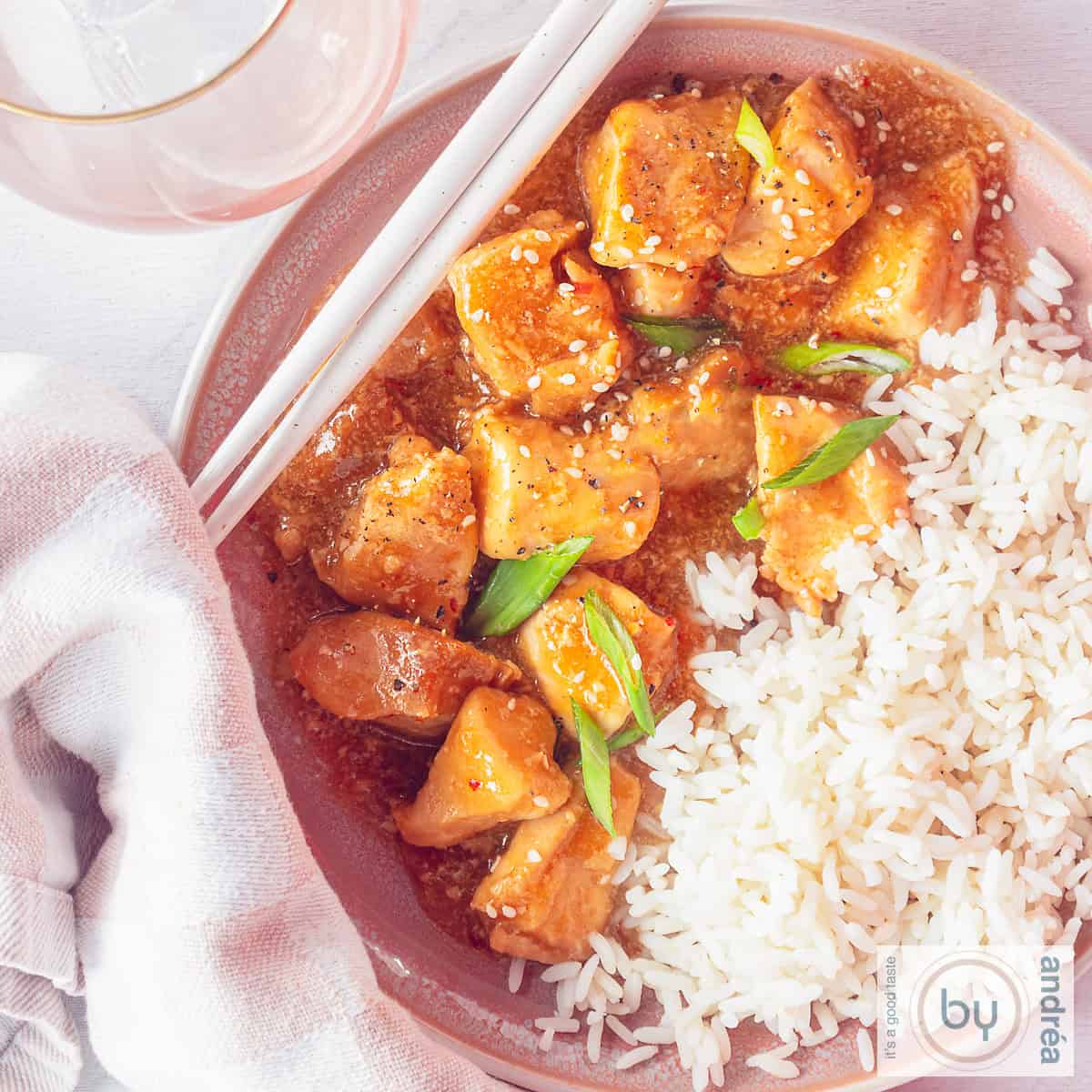 A square photo from above of a bowl half filled with honey garlic chicken and the rest with rice.