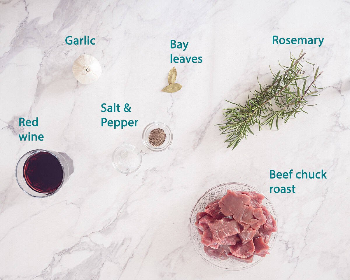 Ingredients Peposo- Italian Slow-Cooked Beef in Red Wine on a white marble background. A text description is there