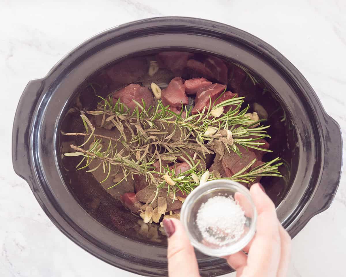 Slow cooker with meat and herbs with added salt