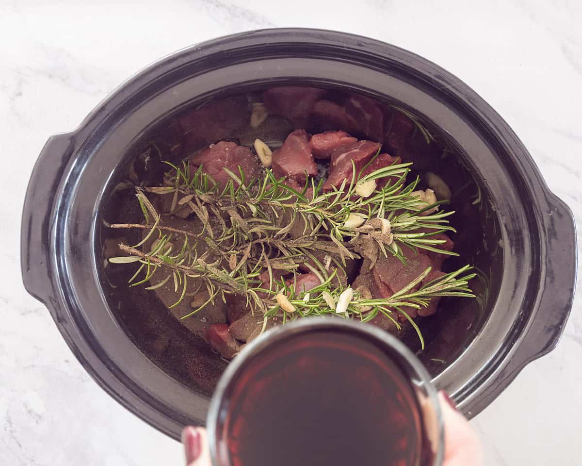 Slow cooker with meat, herbs and wine added