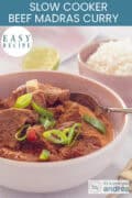 A pink bowl with curry madras with beef and garnish of spring onions. A text at the top: slowcooker beef curry madras, easy recipe