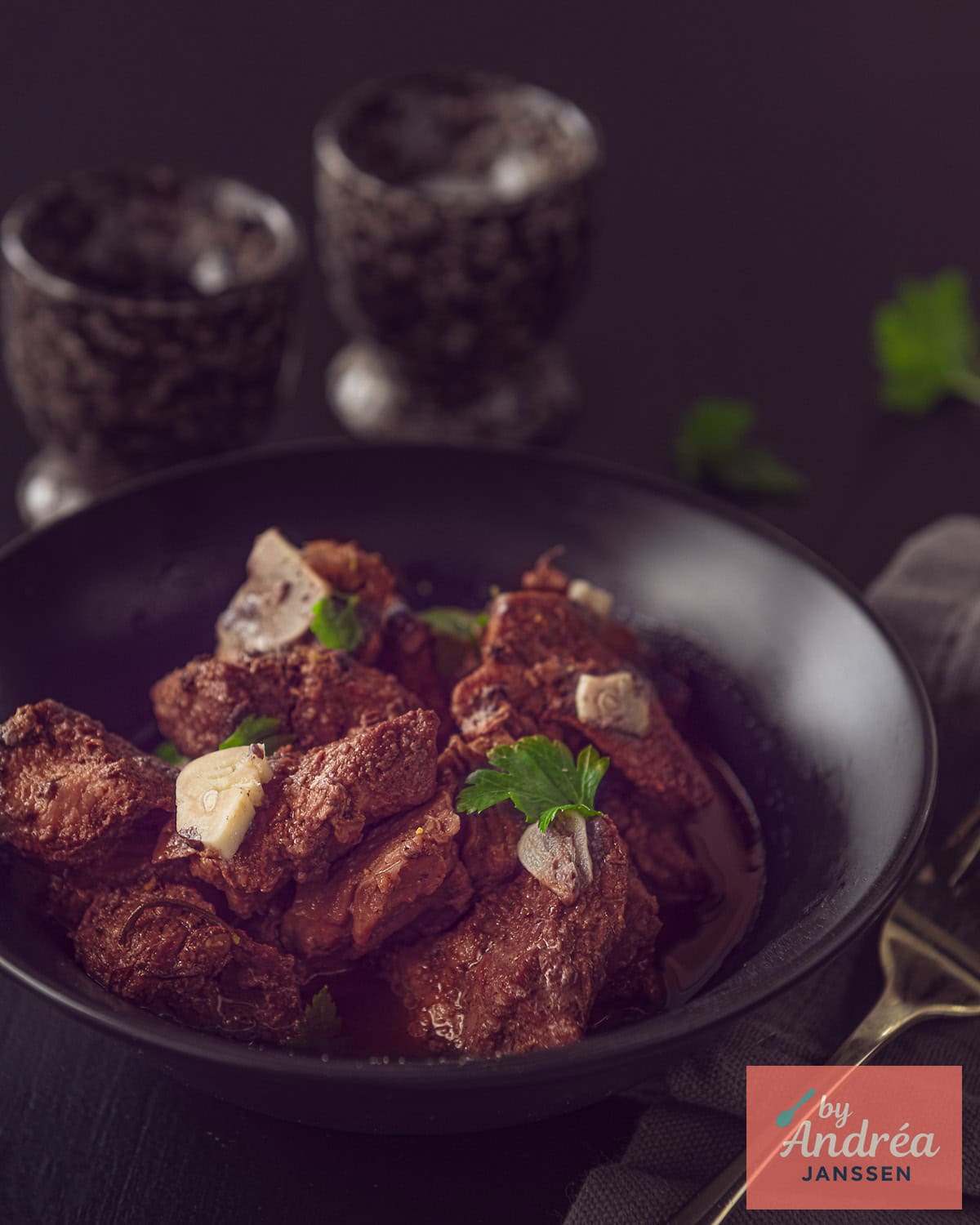 A dish filled with Italian stew with garlic and red wine on a dark background