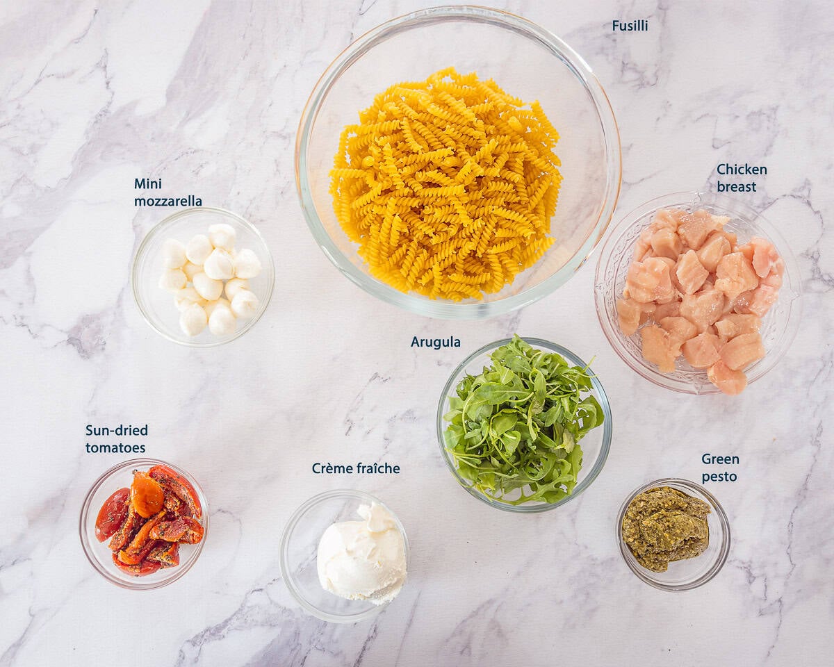 Ingredients 15-Minute Chicken Pesto Pasta on a white marble background with text description