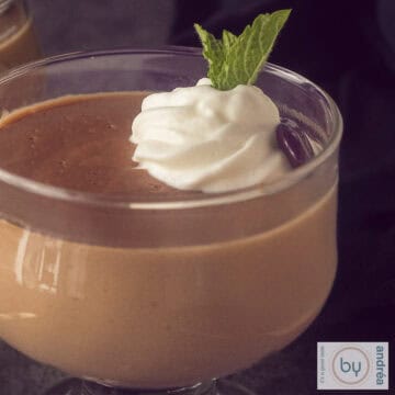 A square photo of a macro shot of hopjesvla with a dollop of whipped cream, a chocolate coffee bean and mint.