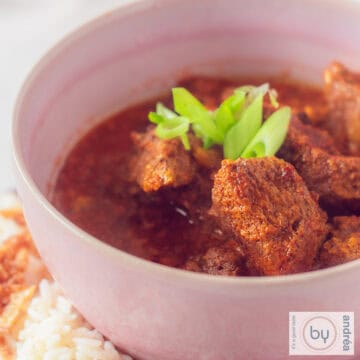 Beef curry with coconut milk in a pink bowl.