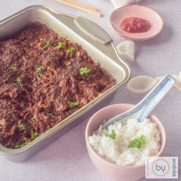 A square photo with a baking tin filled with a frikadel pan, a pink bowl with white rice and a bowl with sambal.