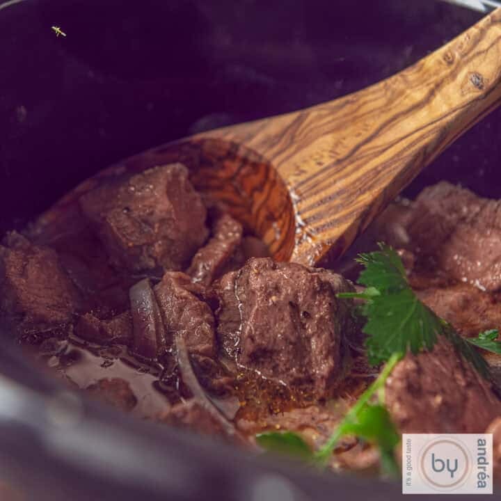 A square photo showing part of a slow cooker containing entrecote with butter sauce.