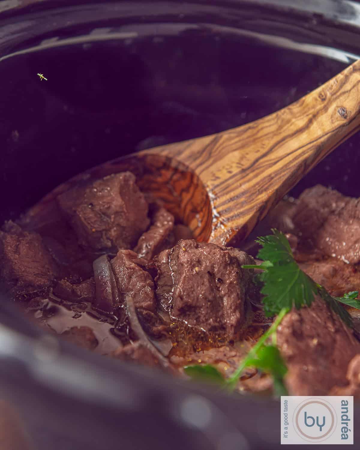 Part of a slow cooker with entrecote, onions and butter sauce.