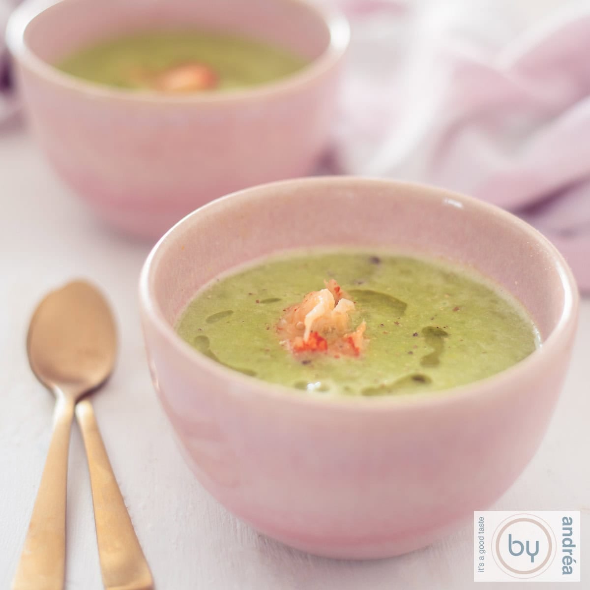 Een roze kom met doperwtjessoep met rivierkreeftjes