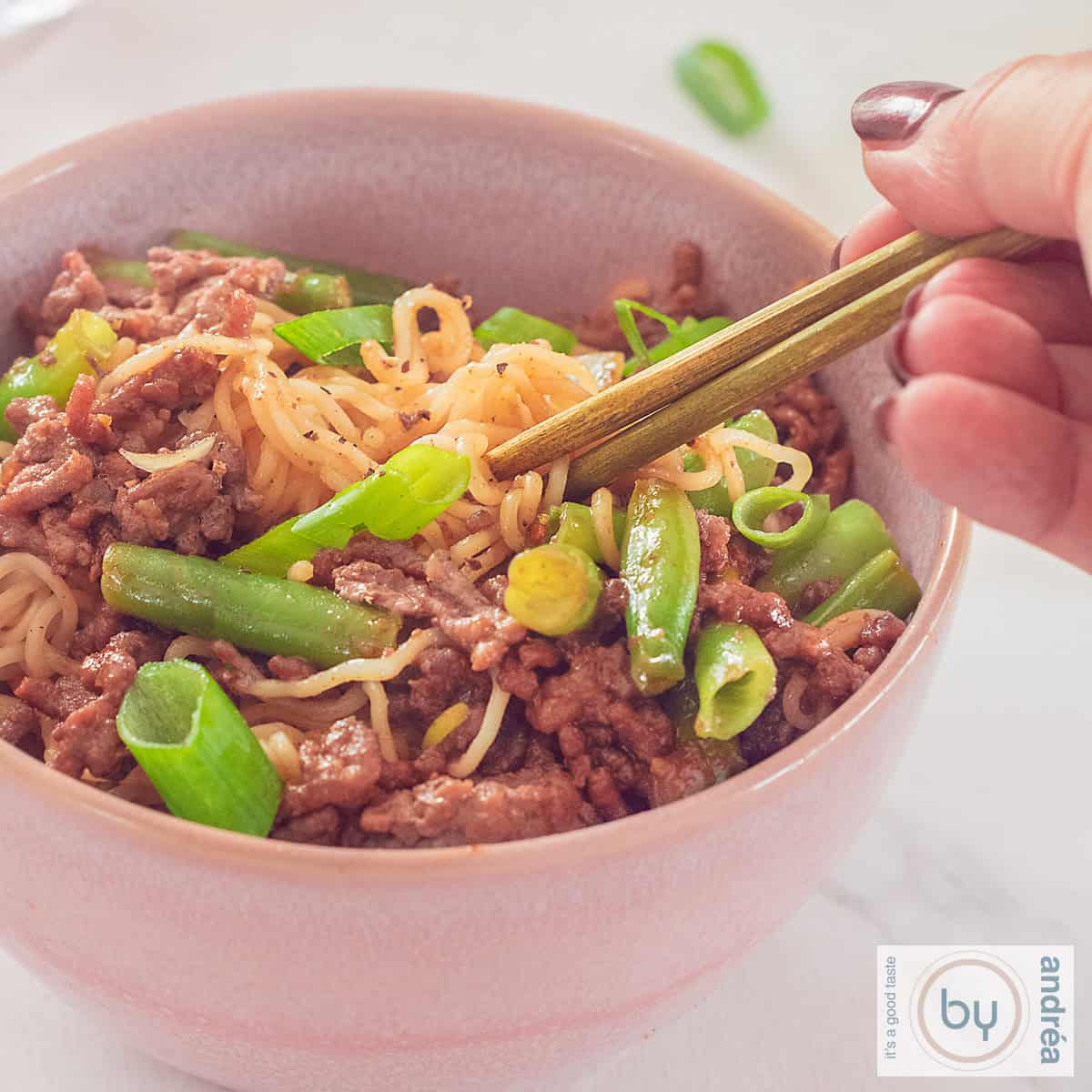 A square photo of a bowl of noodles with green beans and ground beef.