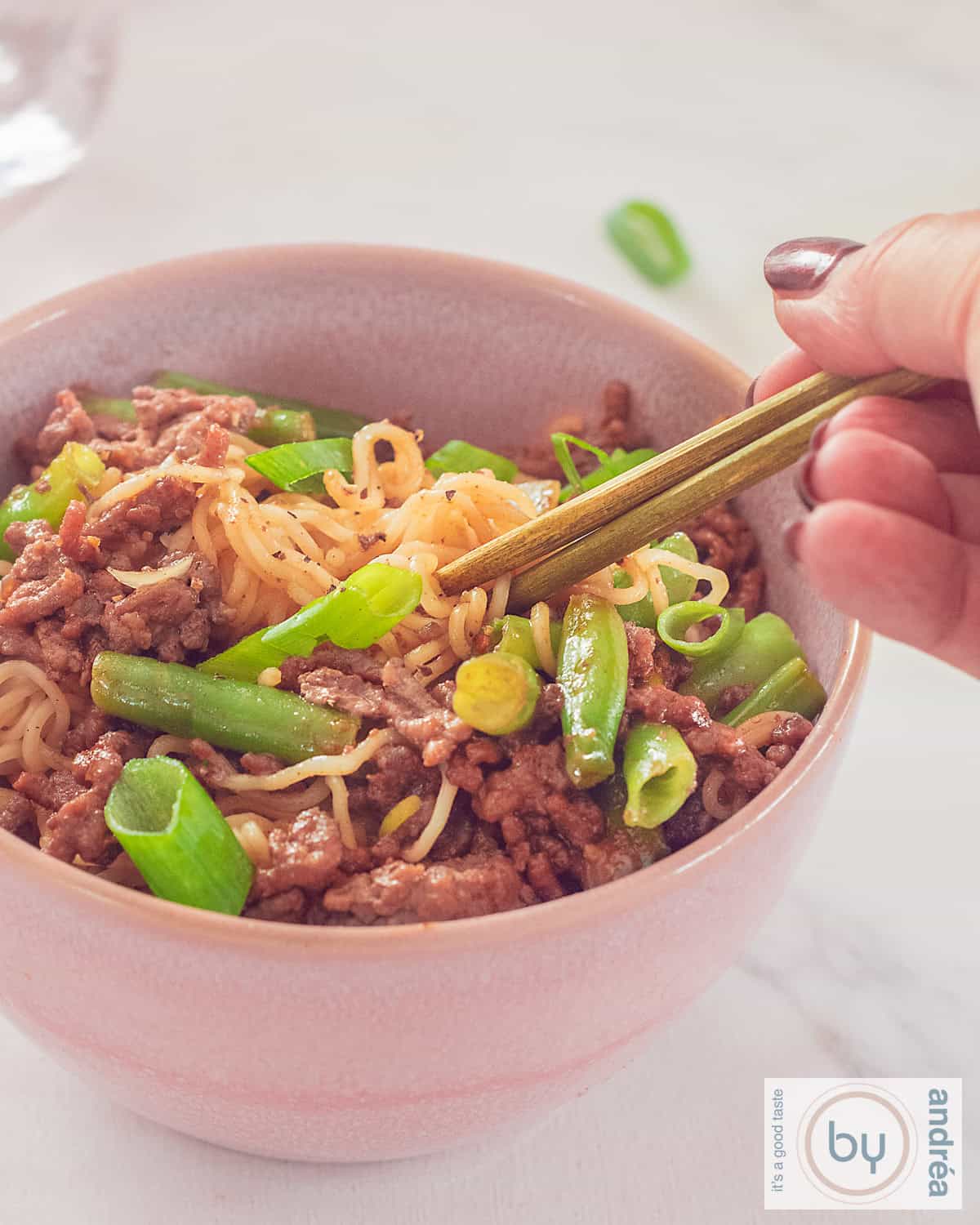 A bowl of noodles, ground beef, green beans in a rich sauce.