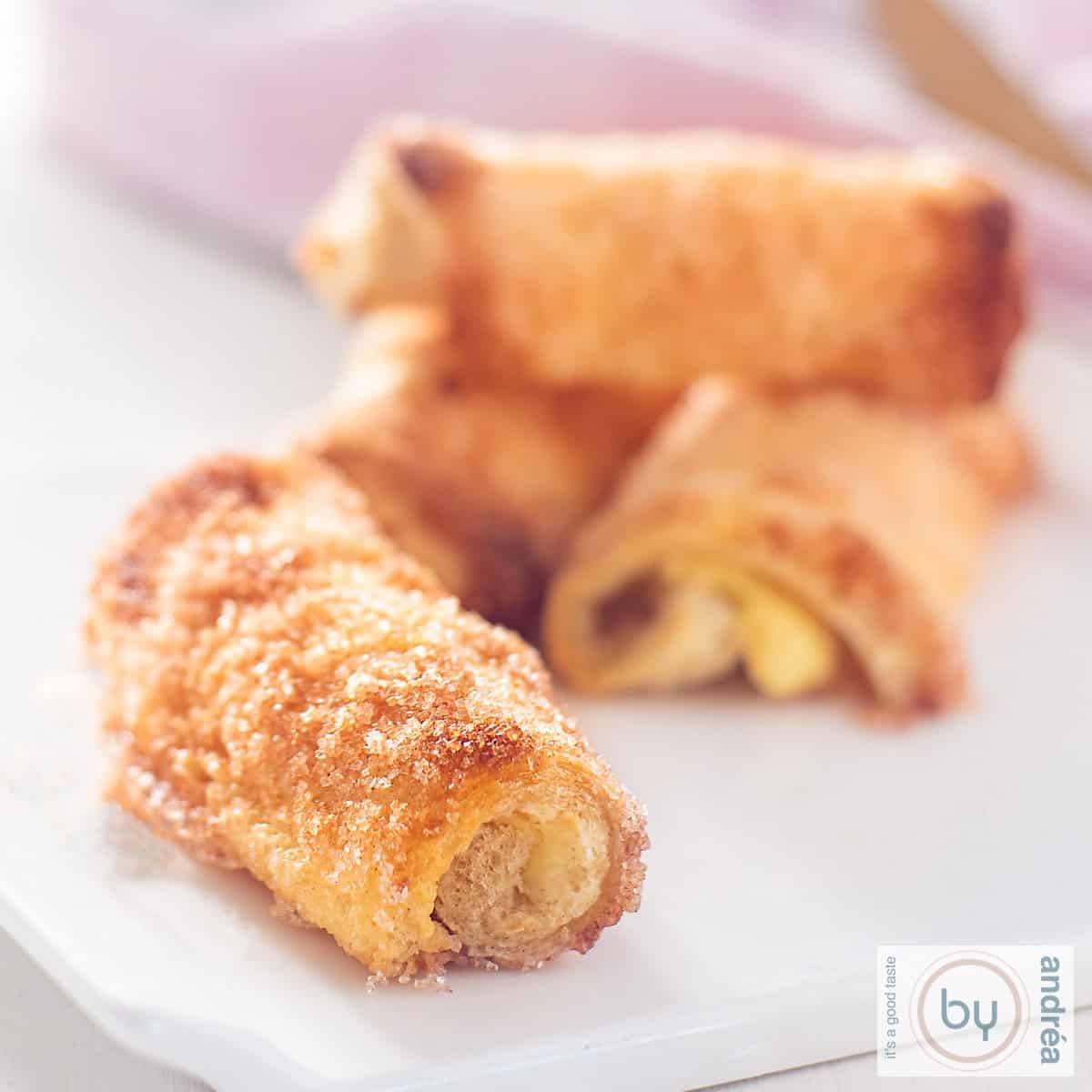 Vier kaneel roomkaas rolletjes op een wit bord.