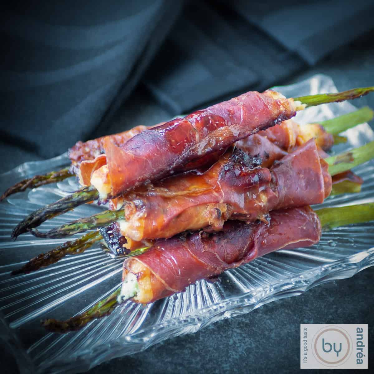 Een vierkante foto met een glazen schaaltje met gegrilde asperges, Boursin en Prosciutto