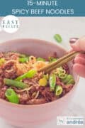 Part of pink bowl with beans, noodles and minced meat in a delicious sauce. A text above: easy recipe 15 minute spicy beef noodles