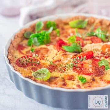 A square photo of a quiche with tomato, mustard and brie