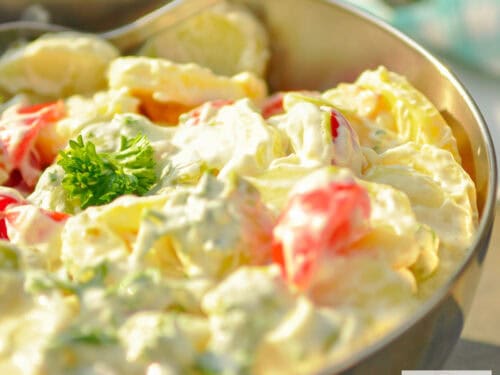 A stainless steel bowl with slim potato salad on a stone surface