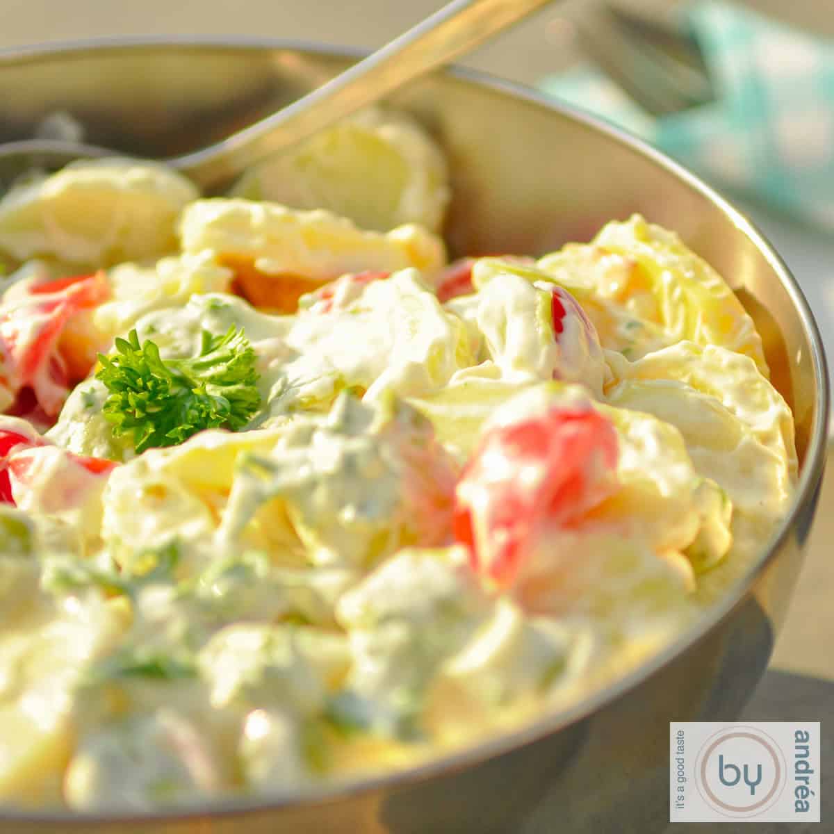 A stainless steel bowl with slim potato salad on a stone surface